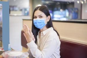 Frau isst im Restaurant mit Protokoll zur sozialen Distanzierung, während sie die Stadt aufgrund einer Coronavirus-Pandemie sperrt