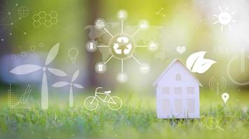 kleines weißes Haus auf grünem Hintergrund mit ökologischen Erhaltungssymbolen, ökologisches Entwicklungstechnologiekonzept foto
