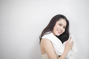 Eine Frau trocknet sich nach dem Duschen die Haare mit einem Handtuch ab