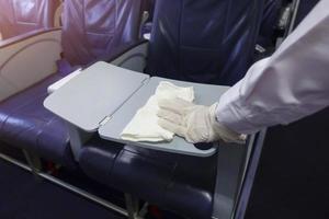 Nahaufnahme Hand trägt Handschuhe, die den Flugzeugsitz für die Covid-19-Präventionspandemie reinigen foto
