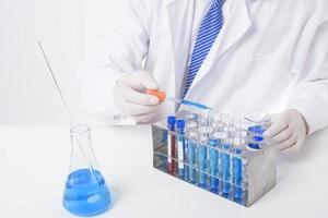 Nahaufnahme des Wissenschaftlers testet und erforscht einige blaue flüssige Chemikalien im Labor isoliert auf weißem Hintergrund.