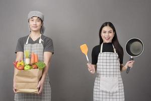 glückliches Paar hält Gemüse in Einkaufstüte im Studio grauen Hintergrund foto