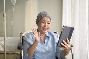 Krebspatientin mit Kopftuch macht Videoanrufe im sozialen Netzwerk mit Familie und Freunden im Krankenhaus. foto