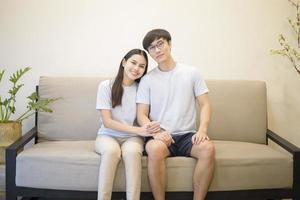 ein glückliches Paar im blauen Hemd sitzt zu Hause auf einem Sofa