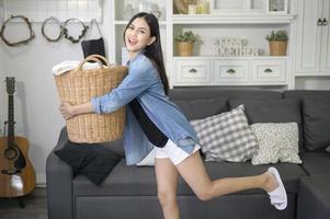 Eine glückliche Haushälterin trägt einen Eimer Tücher für die Wäsche im Haus. foto