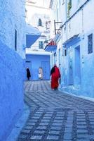 Frauen, die auf einer schmalen Gasse zwischen traditionellen Häusern spazieren gehen foto