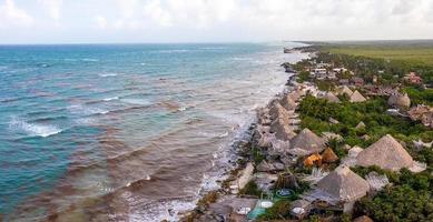 luftige küste von tulum am strand mit einem magischen karibischen meer und kleinen hütten an der küste. foto