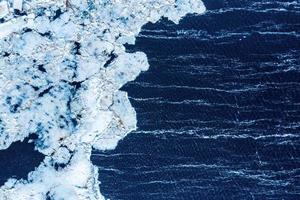 Eis Textur Hintergrund. strukturierte kalte frostige Oberfläche des Eisblocks auf dunklem Hintergrund. foto