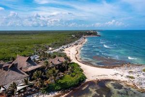 luftige küste von tulum am strand mit einem magischen karibischen meer und kleinen hütten an der küste. foto