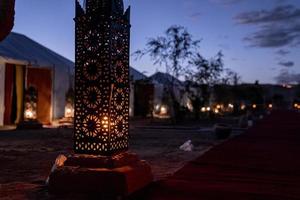 beleuchtete Laternen neben Zelten in der Wüste gegen den Himmel während der Dämmerung foto