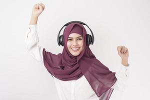 Porträt der schönen Frau mit Hijab ist viel Spaß beim Musikhören auf weißem Hintergrund
