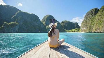Blick auf eine Frau im Badeanzug, die auf einem traditionellen thailändischen Longtail-Boot über schöne Berge und das Meer, die Phi-Phi-Inseln, thailand, genießt