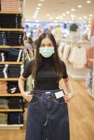 Frau mit Gesichtsmaske kauft Kleidung im Einkaufszentrum