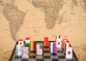 Ländersymbole auf dem Schachbrett vor dem Hintergrund der politischen Weltkarte. politische Spiele. foto