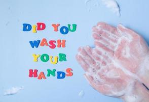 farbiger Schriftzug hast du deine Hände neben deinen Händen in Schaum auf farbigem Hintergrund gewaschen foto