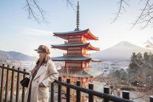 Schöne Touristin trägt Gesichtsmaske auf der Chureito-Pagode und dem Fuji-Berg, Japan, Reisen unter dem Konzept der Covid-19-Pandemie foto