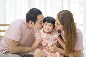 Porträt einer glücklichen asiatischen Familie im weißen Schlafzimmer foto