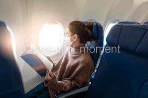 Eine junge Frau mit Gesichtsmaske reist im Flugzeug, neue normale Reise nach dem Konzept der Covid-19-Pandemie foto