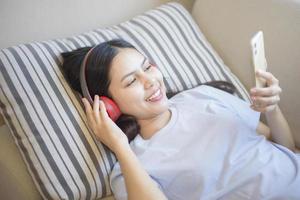 Eine junge Frau verwendet ein Headset, das Musik im Wohnzimmer genießt, ein Sicherheitskonzept für zu Hause foto
