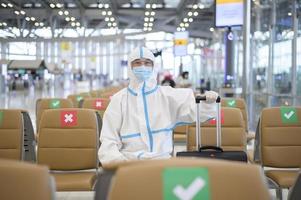 Ein asiatischer Mann trägt einen PSA-Anzug auf dem internationalen Flughafen, Sicherheitsreisen, Covid-19-Schutz, Konzept der sozialen Distanzierung foto