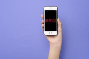 Frauenhand hält Smartphone mit Netflix-Logo auf Apple iPhone Se foto