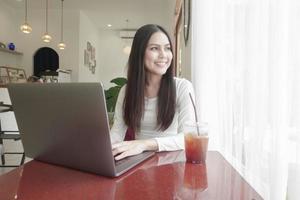 Eine junge Frau arbeitet mit ihrem Laptop im Café foto