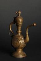 alte orientalische Teekanne aus Metall auf dunklem Hintergrund. antikes Bronzegeschirr foto
