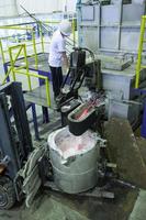 Fabrikarbeiter zum Schmelzen von Aluminiummetall im Eimer, der auf der Lademaschine steht foto