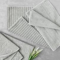weiches Handtuch mit einer Blume in einem grauen dekorativen Stuckhintergrund. Draufsicht, isoliert