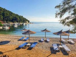 Unberührter Blick auf die Bucht einer griechischen Insel mit leeren Liegestühlen und Sonnenschirmen. foto