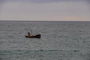 ein fischer und sein boot entlang der küste des ligurischen meeres, während er mit dem fischen beginnt foto