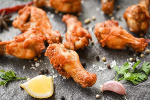 gebratene hähnchenflügel auf schwarzem teller mit zitronen-chili-kräutern und gewürzen - gebackene hähnchenflügel bbq foto