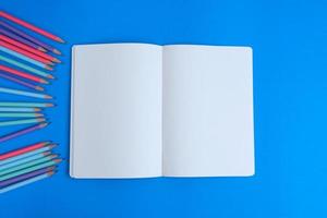 leeres notizbuch, ein bleistift und platz befinden sich auf einem blauen schreibtisch. flach liegend, draufsicht bildungskonzept foto