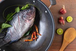 frischer Fisch in einer Pfanne und Gewürzen zum Kochen foto