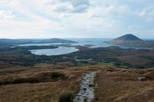 schöne irische Landschaft an einem bewölkten Tag. Hügel, Seen und ein Weg aus Stein. foto