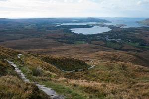schöne irische Landschaft von der Spitze eines Hügels aus gesehen. grüne felder, steinweg und der atlantische ozean im hintergrund foto