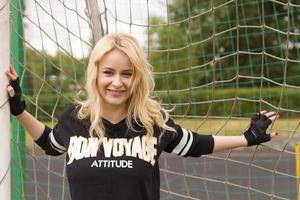 Schöne Blondine im Fußballgitter hält und lächelt. foto