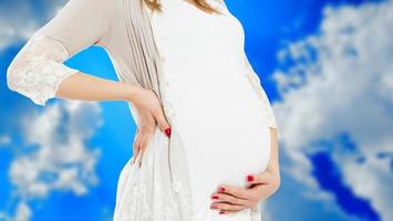 schwangere Frau in Freizeitkleidung isoliert auf verschwommenem Himmelshintergrund, schwangere Frau in Freizeitkleidung isoliert auf blauem Hintergrund, schwangere schöne Dame, die ein Baby erwartet foto