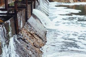 Wasser fließt schnell in einer Kaskade entlang der Betonwand des Damms. Damm. foto