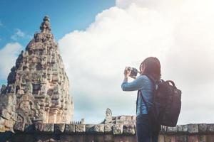 junge attraktive fotografin touristin mit rucksack, die kommt, um ein foto im alten phanom-sprossentempel in thailand zu schießen.