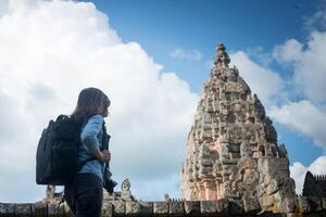 junge attraktive fotografin touristin mit rucksack, die kommt, um ein foto im alten phanom-sprossentempel in thailand zu schießen.