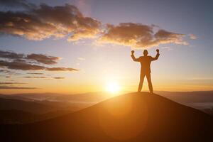 Silhouette erfolgreicher Mann auf der Spitze des Hügels und den Sonnenuntergang foto