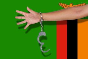 Handschellen mit Hand auf Sambia-Flagge foto