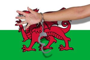 Handschellen mit Hand auf Wales-Flagge foto