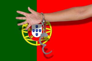 Handschellen mit Hand auf Portugal-Flagge foto