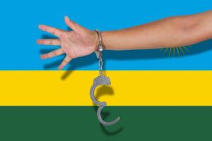 Handschellen mit Hand auf Ruanda-Flagge foto