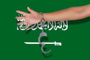 Handschellen mit Hand auf saudi-arabischer Flagge foto