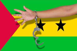 handschellen mit der hand auf der flagge von sao tome und principe foto