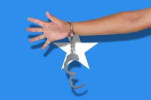 Handschellen mit Hand auf Somalia-Flagge foto