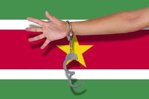 handschellen mit der hand auf der suriname-flagge foto